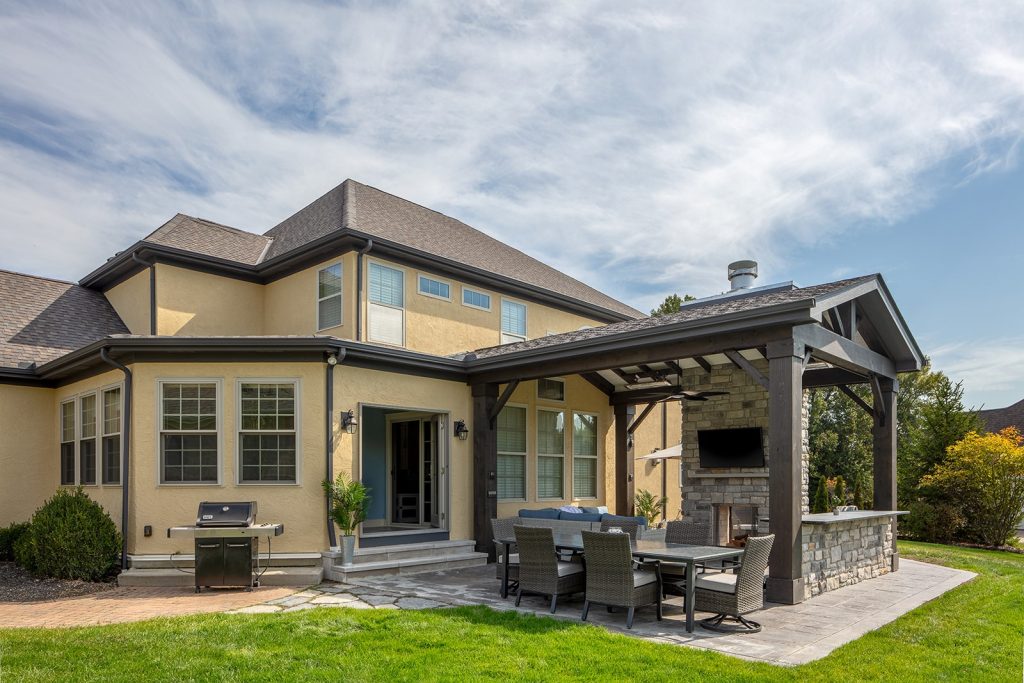 a sunroom & outdoor living addition featuring a fabulous two-sided stone fireplace and timber frame pavilion.