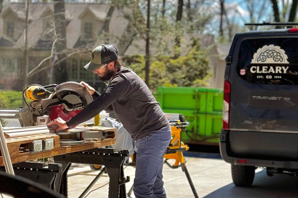Cleary team member cuts lengths of wood using a circular saw in the driveway of a client's home